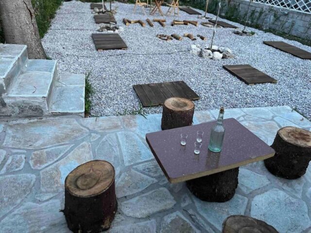 Outdoor yard with rustic wooden seating and table in Pavliani Oiti – αυλή με παραδοσιακά ξύλινα καθίσματα στην Παύλιανη Οίτης